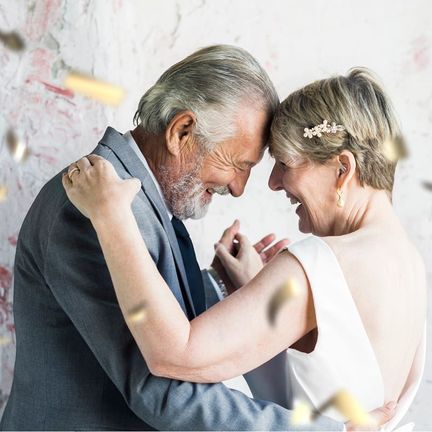 An older couple leans their heads together while dancing