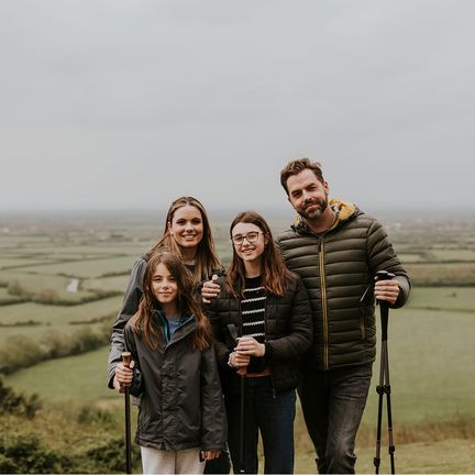A family of four with hiking poles on a hill