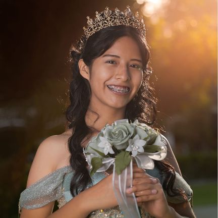 A girl in a formal dress and tiara at her quinceañera