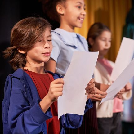A group of children singing while holding sheet music