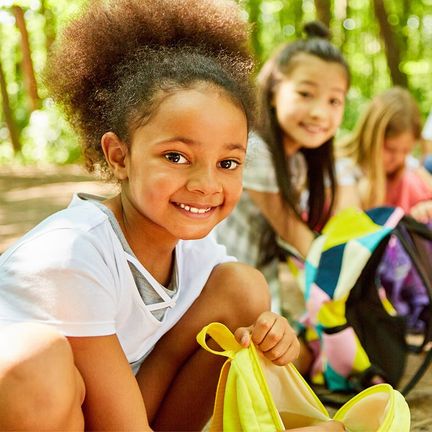 Kids kneeling with their backpacks at summer camp