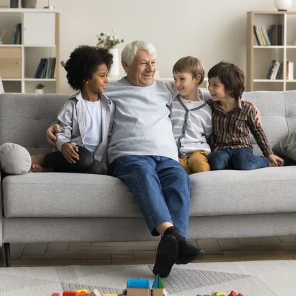 An older man sharing stories with three children on a couch