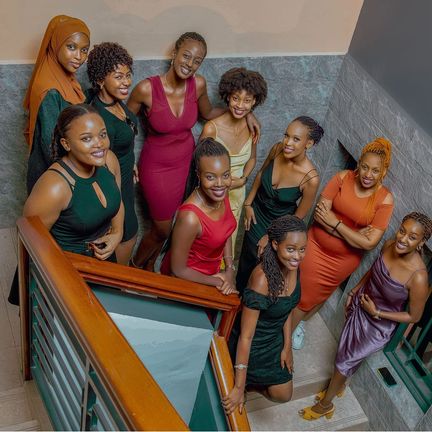 A group of women in dresses pose on a staircase